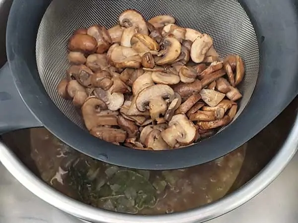 Sautéed mushrooms in fine mesh strainer.