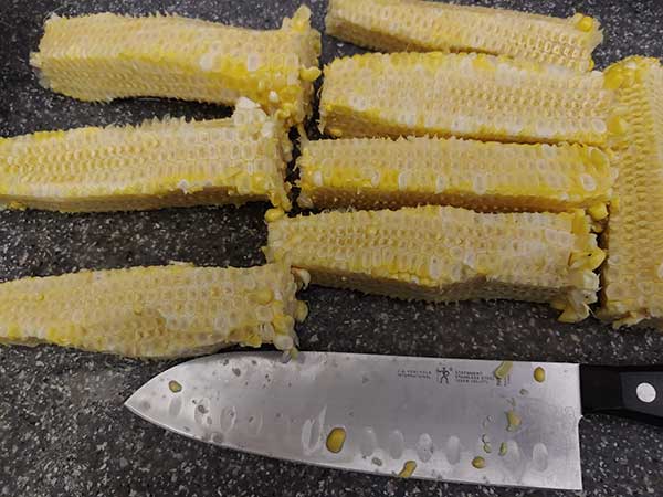 Corn cobs on cutting board with kernels removed.