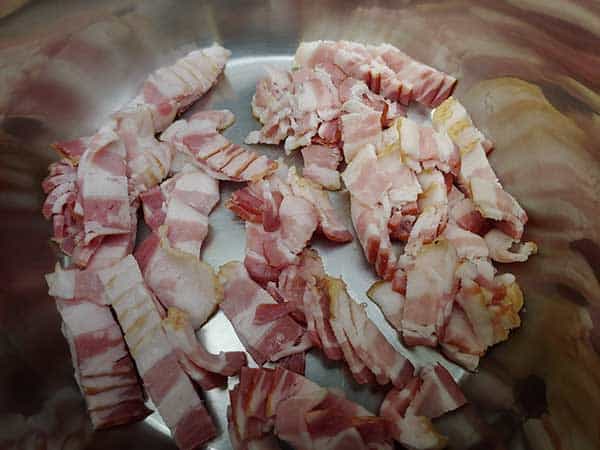Uncooked bacon pieces in pot.