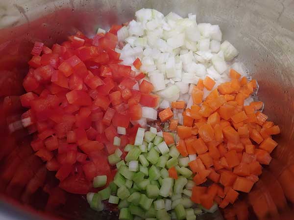 Diced onions, red peppers, carrots, and celery in pot.