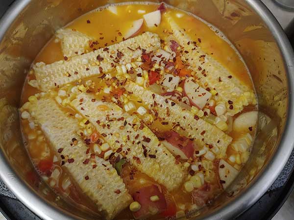 Red pepper flakes sprinkled over chowder in pot.