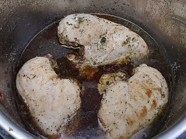 Cooked chicken breasts in ranch-flavored broth.