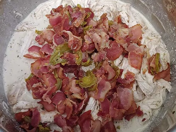 Bacon and jalapeÃ±os on top of shredded chicken.