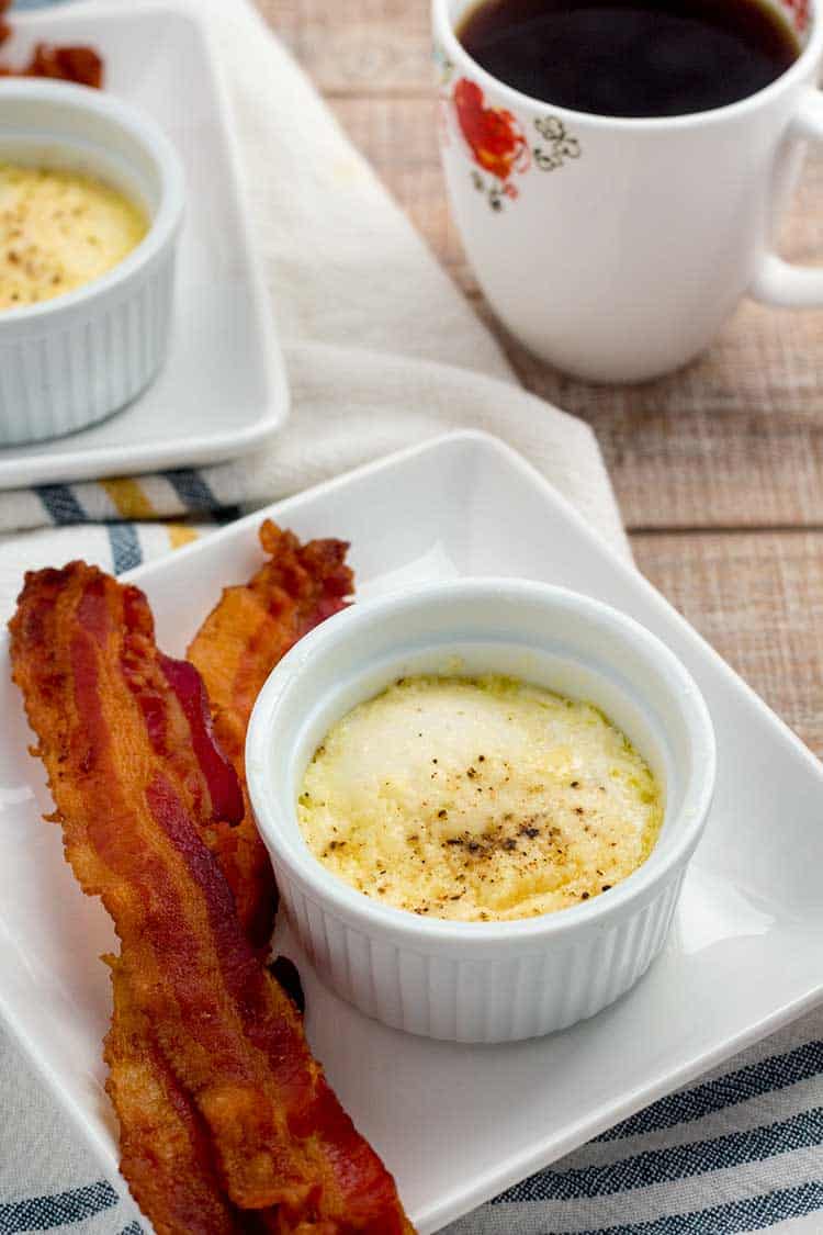 Baked eggs in ramekin with bacon and coffee on the side.