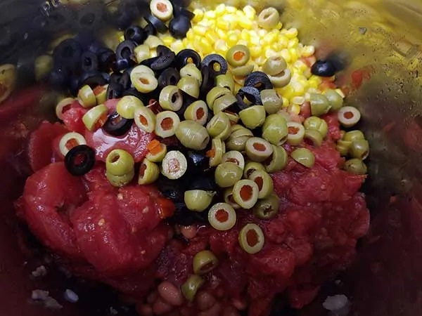 Sliced green and black olives o top of corn and tomatoes.