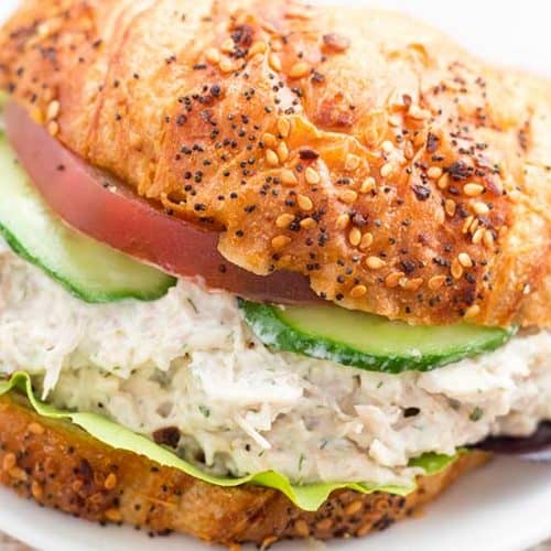Chicken salad sandwich on croissant with tomato and cucumbers.