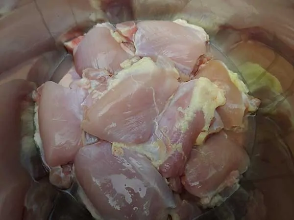 Uncooked chicken thighs in pot.