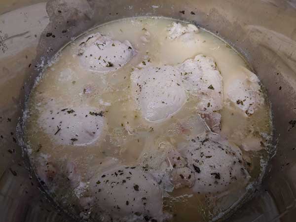 Cooked chicken thighs in broth.