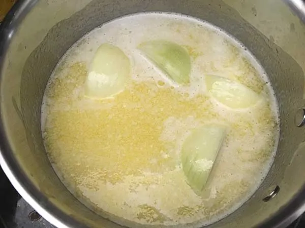 Melted butter in pot with quartered onion.
