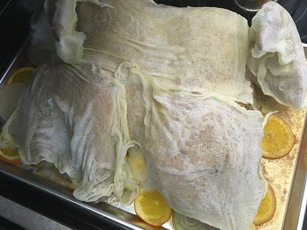 Covering turkey in butter-dipped cheesecloth.