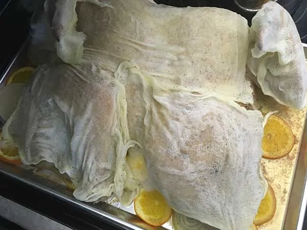 Covering turkey in butter-dipped cheesecloth.