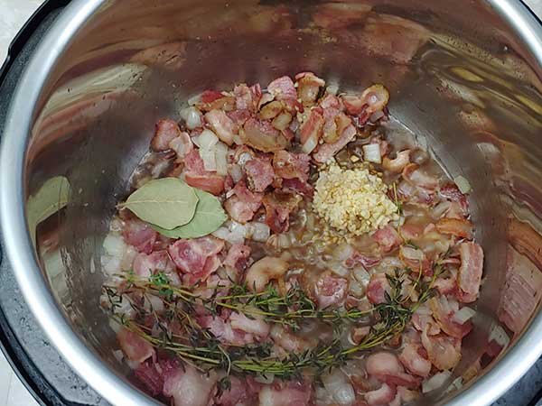 Sautéed bacon and onions topped with thyme sprigs, garlic, and bay leaves.