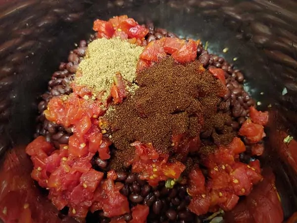 Spices on top of black beans and dice tomatoes.