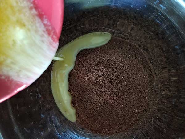 Pouring melted butter into graham cracker crumbs.