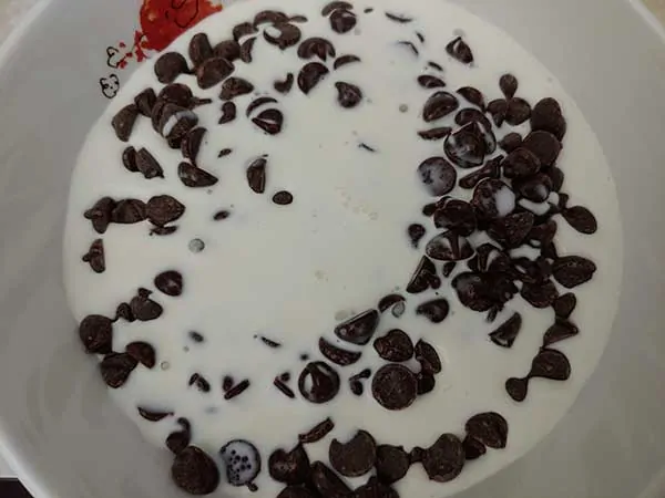 Chocolate chips and heavy cream in bowl.
