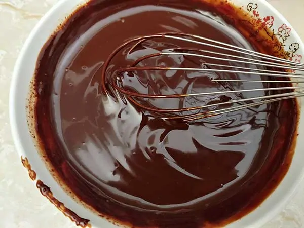 Melted chocolate with whisk in bowl.