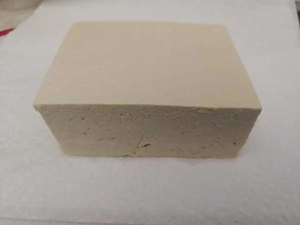 Block of tofu on white paper towels.