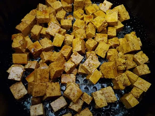 Uncooked cubes of marinated tofu in air fryer.