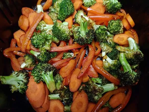 Cooked veggies in air fryer basket.