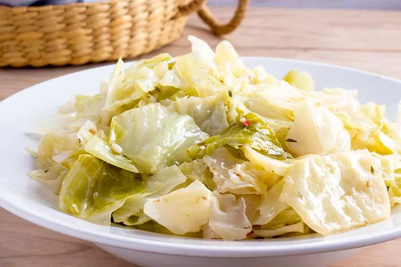 Instant Pot cabbage in white bowl with basket in background.
