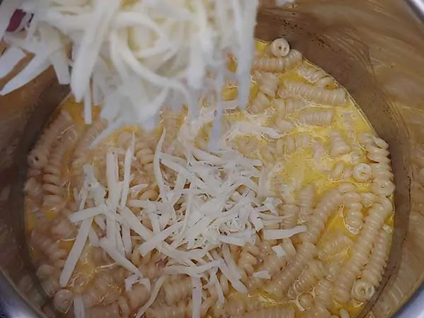 Adding shredded cheese to pasta.