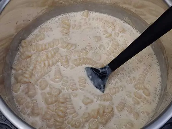 Mixing mac and cheese with rubber spatula.