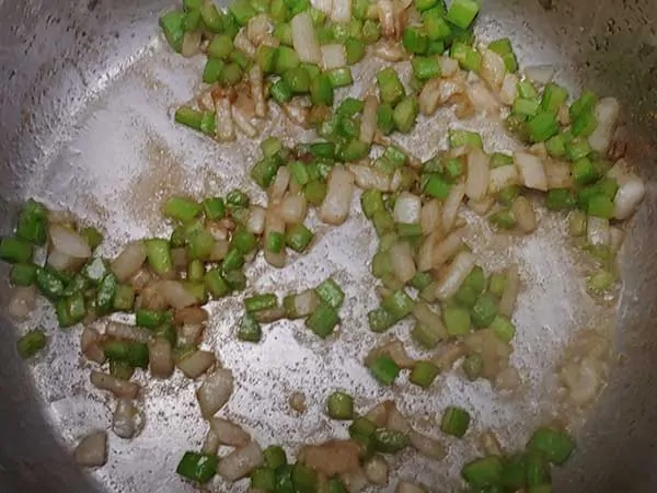 Diced onion and celery in pot seasoned with coriander.