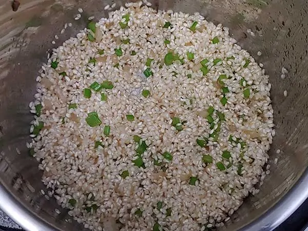 Arborio rice in pot with onions and celery.