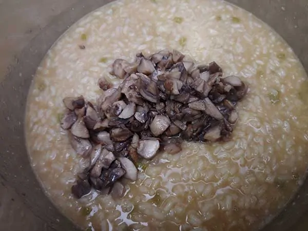 Cooked risotto in pot topped with mushrooms.