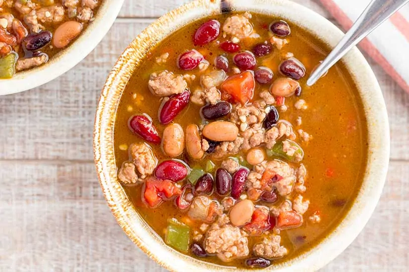 Two bowls of turkey chili on wood background.