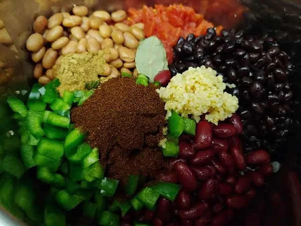 Chili vegetables in pot, topped with spices, garlic, and bay leaves.