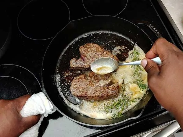 Basting filets with butter in cast iron skillet.
