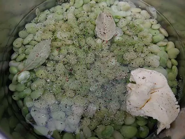 Frozen baby lima beans in water with bay leaves and butter.