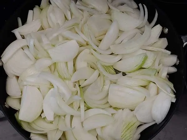 Sliced onions in nonstick pan.