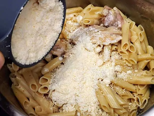 Topping chicken and pasta with grated parmesan cheese.