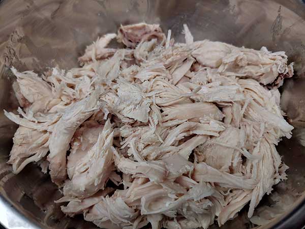 Shredded chicken in mixing bowl.