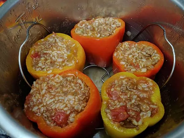 Uncooked bell peppers filled with sauce mixture in Instant Pot.