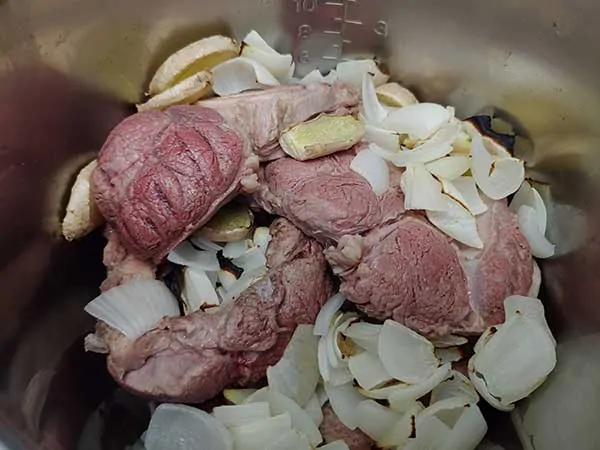 Beef shanks, charred onions in ginger in pot.