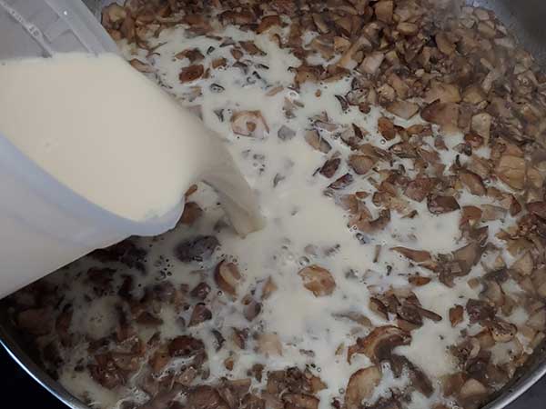 Pouring cornstarch slurry into mushrooms.