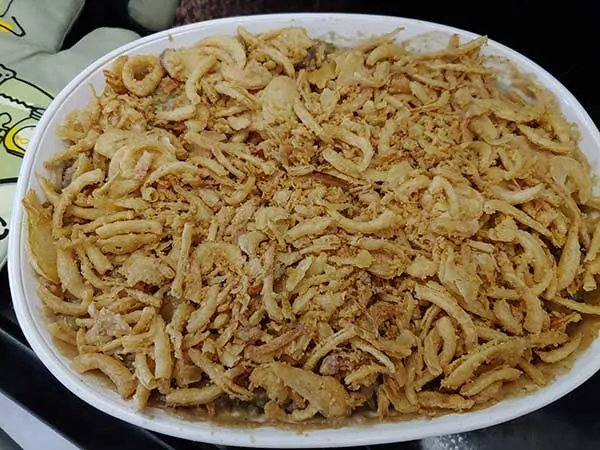 Vegan green bean casserole in dish topped with fried onions.