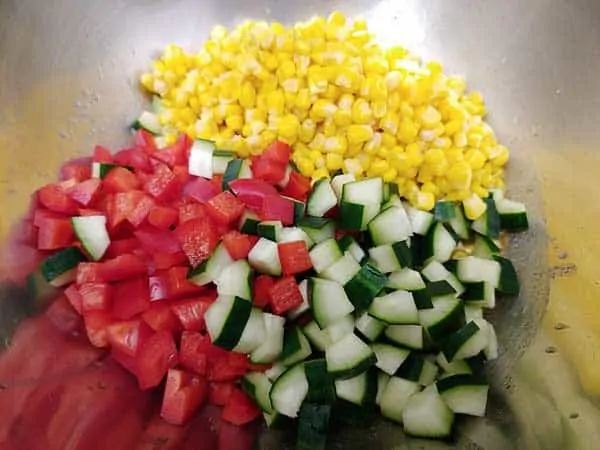 Red peppers, corn, and cucumbers in mixing bowl.