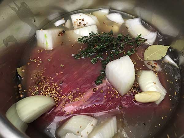 uncooked corned beef brisket topped with chicken broth and aromatics