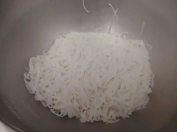 Cooked rice noodles in large mixing bowl.