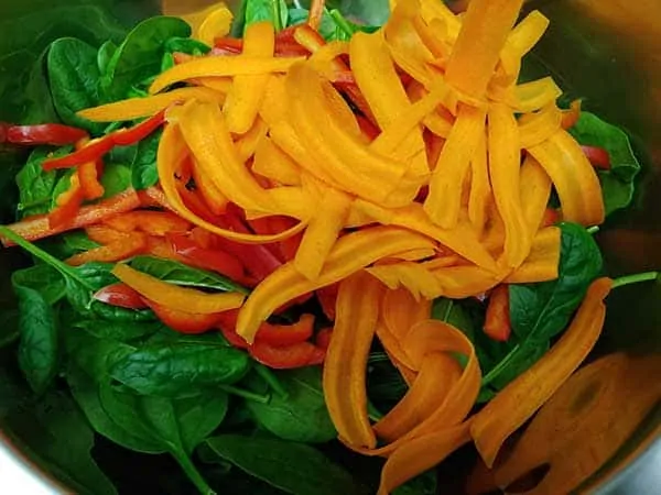 Spinach, peppers, and carrots in mixing bowl.
