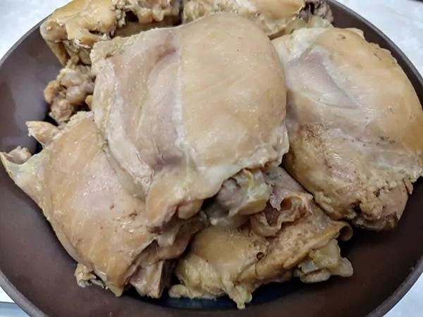 Cooked chicken thighs in brown bowl.