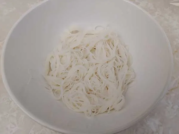 Cooked rice noodles in white bowl.