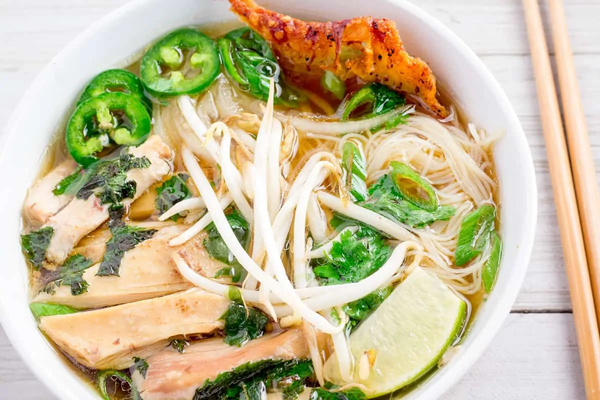 Instant Pot chicken pho in white bowl with chopsticks.