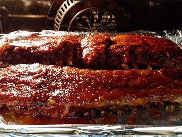 baby back ribs with sauce broiling in oven.