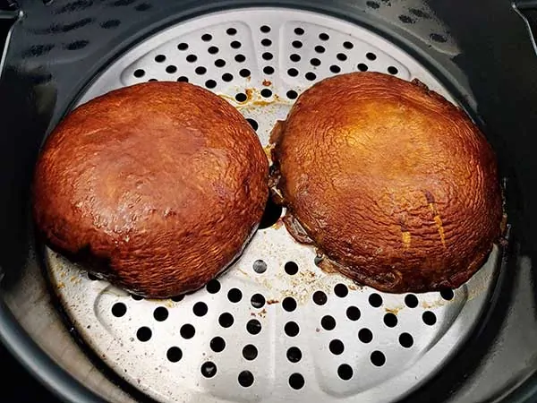 two cooked portobello mushrooms in air fryer.