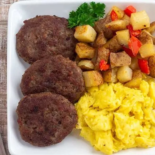 Homemade Italian Sausage patties on plate with eggs and potatoes.